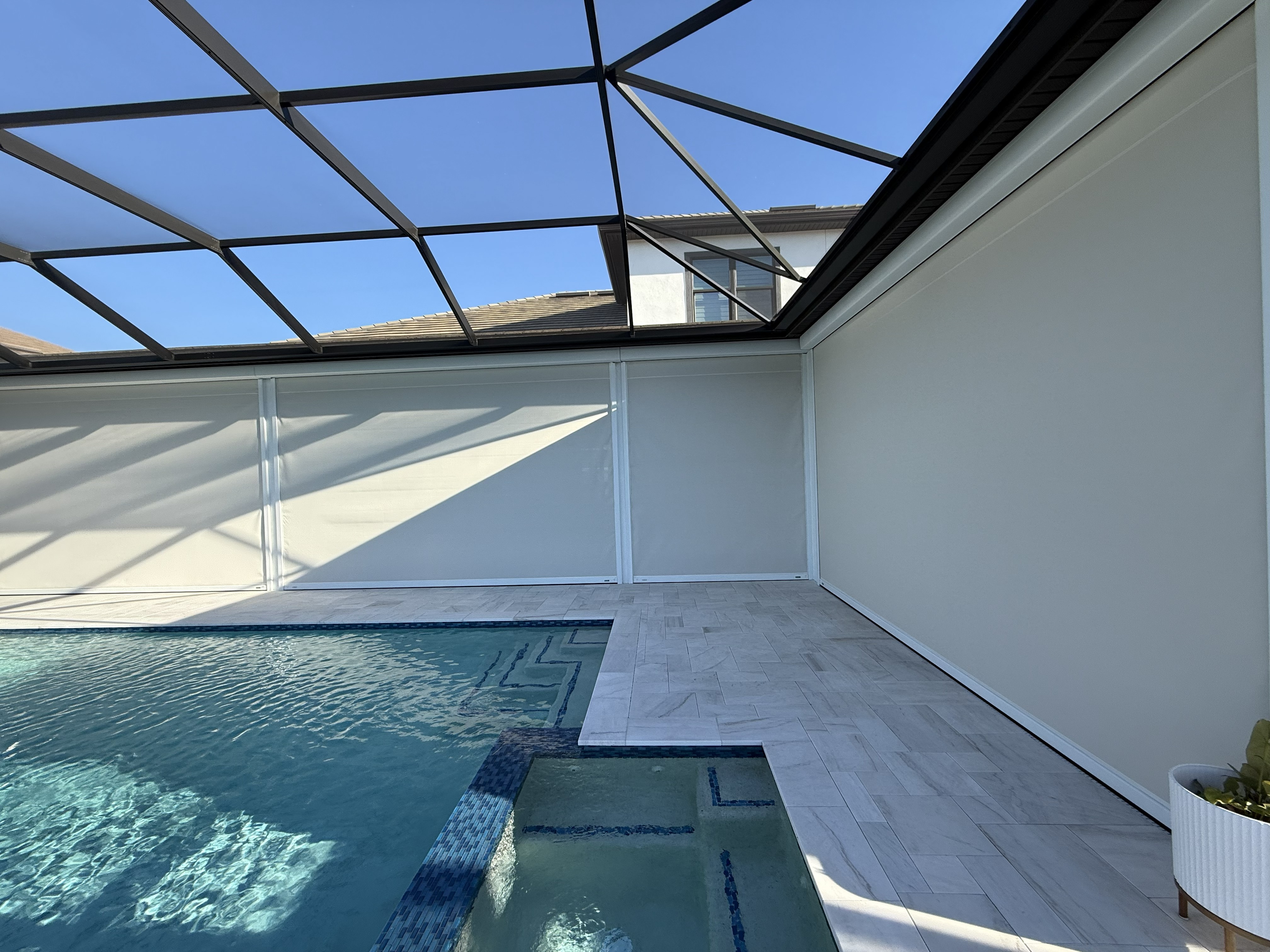 White motorized screens fully deployed around a pool lanai in Sarasota