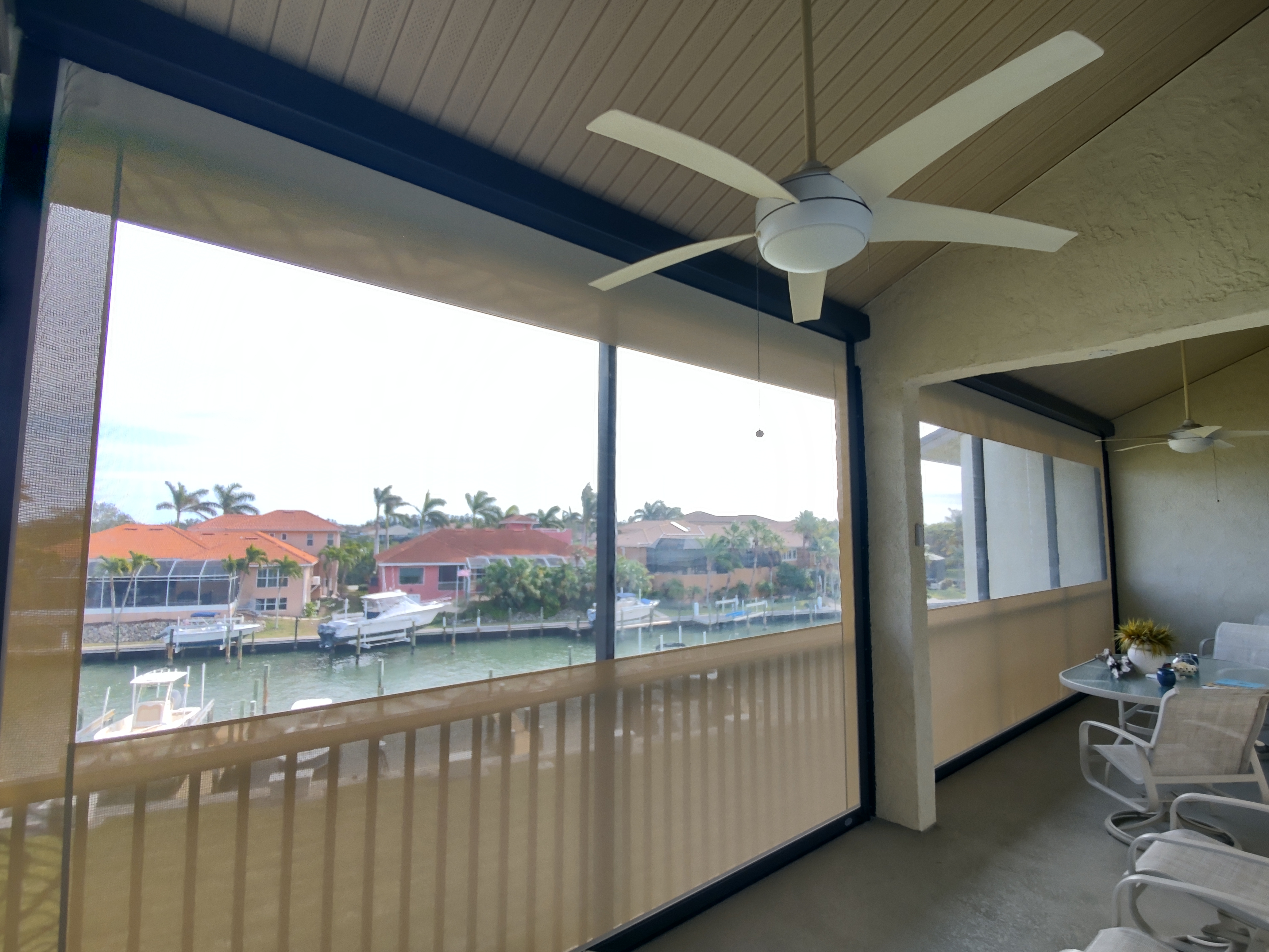 Motorized roll-down screens on a waterfront condo balcony overlooking a Sarasota marina