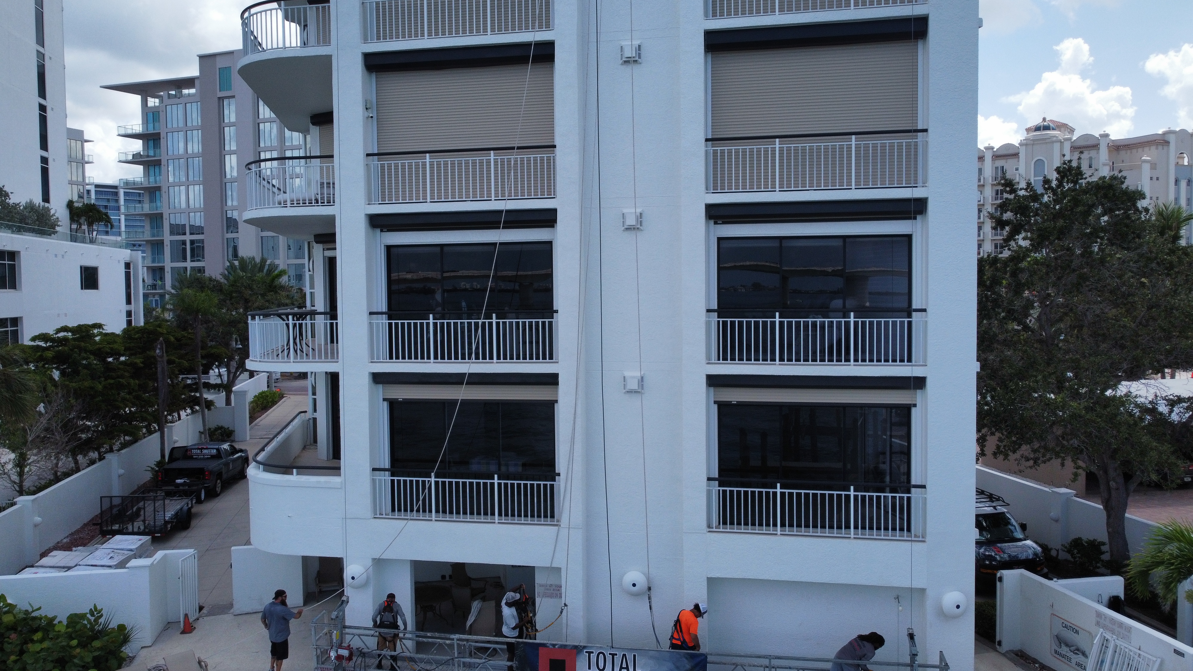 Aerial drone view of a 5-story Sarasota beachfront condo with hurricane shutters on every unit